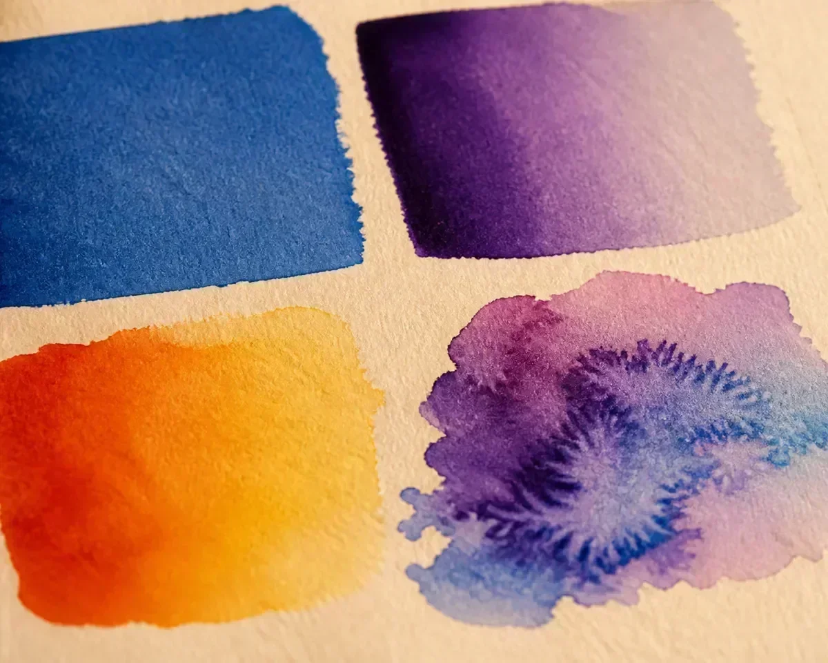 Four watercolor wash technique examples on textured paper showing flat, graduated, variegated, and wet-on-wet effects